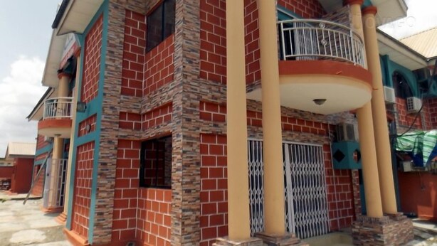 A multi-story building with a brick facade, a balcony with a metal railing, and a security gate. - SureRest Hotel & Suites (Lagos)