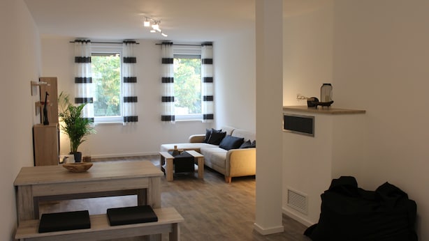 A modern living room with a sofa, coffee table, and a dining area with a bench.