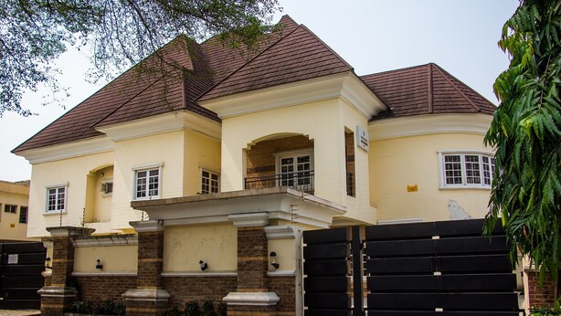 A two-story house with a brick facade, a balcony, and a gated entrance. - Chelsea Suites Annex (Lagos)