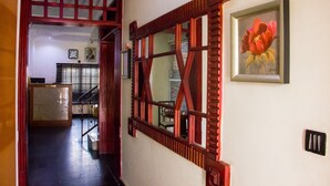 A hallway with a wooden door frame, a reception desk, and a framed artwork on the wall. - Chelsea Suites Annex (Lagos)