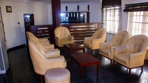 A lobby with leather armchairs, a wooden bench, and a small ottoman. - Chelsea Suites Annex (Lagos)