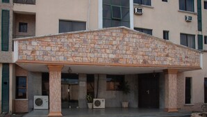 A building with a stone facade, columns, and a covered entrance. - Alfoscar Hotel & Suites (Lagos)