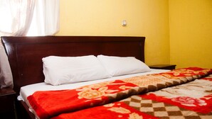 A bed with white pillows and a red and beige floral blanket. - Alfoscar Hotel & Suites (Lagos)