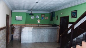 A lobby with a reception desk, a staircase, and a wall with clocks and framed certificates. - Alfoscar Hotel & Suites (Lagos)