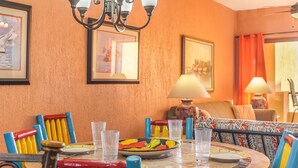 A dining area with a round table, colorful chairs, and a chandelier. - C 401 Spacious Well Furnished Ocean View Condo (Puerto Peñasco)