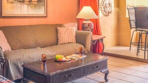 A cozy living room with a sofa, a coffee table with snacks, a lamp, and a painting of boats. - C 401 Spacious Well Furnished Ocean View Condo (Puerto Peñasco)