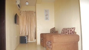 A living room with two sofas, a small TV, a heater, and a curtain. - Bella Rose Hotel (Lagos)