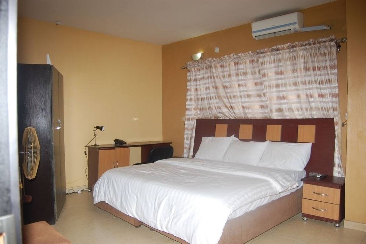 A bedroom with a bed, bedside table, and a desk with a chair.