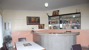 A bar area with a counter, seating, and a fan. - Bella Rose Hotel (Lagos)