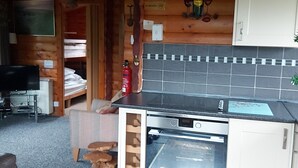 A compact kitchen with a built-in oven, a small countertop, and a wooden ceiling.
