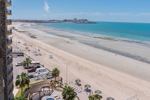A beach resort with a pool area, beach umbrellas, and a view of the ocean.