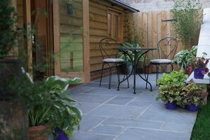 A patio with a table and chairs, surrounded by potted plants and a wooden fence. - Enchanting rural setting in the Garden of England (Old Wives Lees)