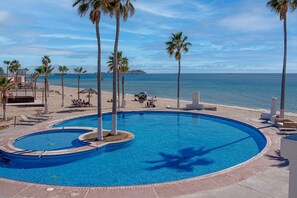A swimming pool with palm trees, a beach, and a view of the ocean. - Casa Blanca CC-405 Ocean's Edge Ocean View (Puerto Peñasco)
