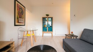 A modern living room with a grey sofa, a round black table, a glass dining table with chairs, a wooden cabinet, and a framed artwork on the wall. - Stylish boutique apartment in trendy West Didsbury (Manchester)