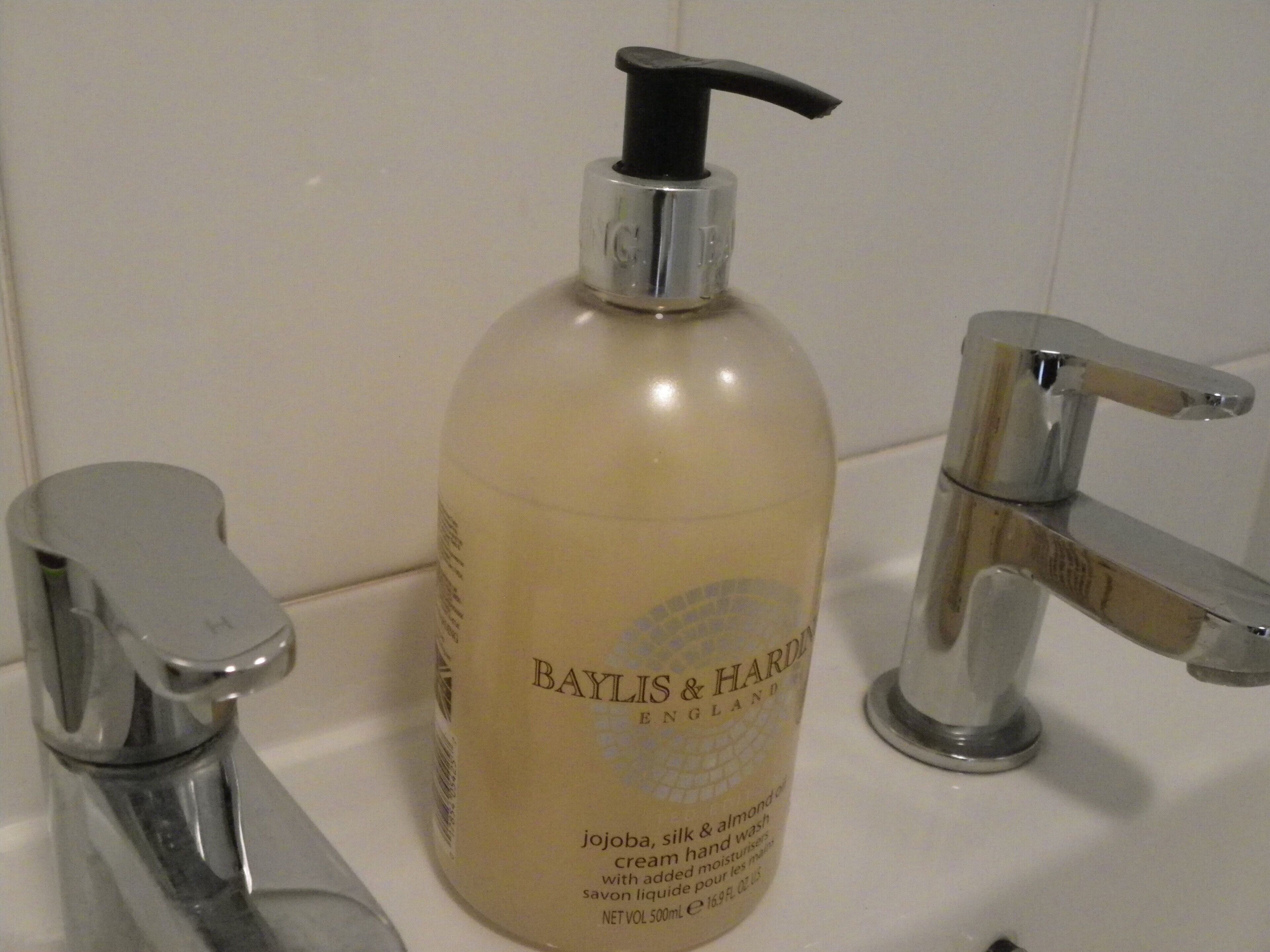 A bathroom with a white sink, a chrome faucet, and a bottle of Baylis & Hardie hand wash.