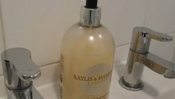 A bathroom with a white sink, a chrome faucet, and a bottle of Baylis & Hardie hand wash.