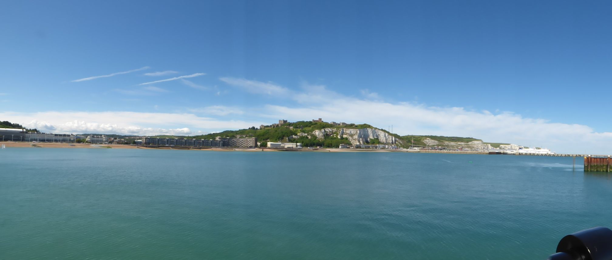 A coastal view with a prominent hill and buildings in the background.