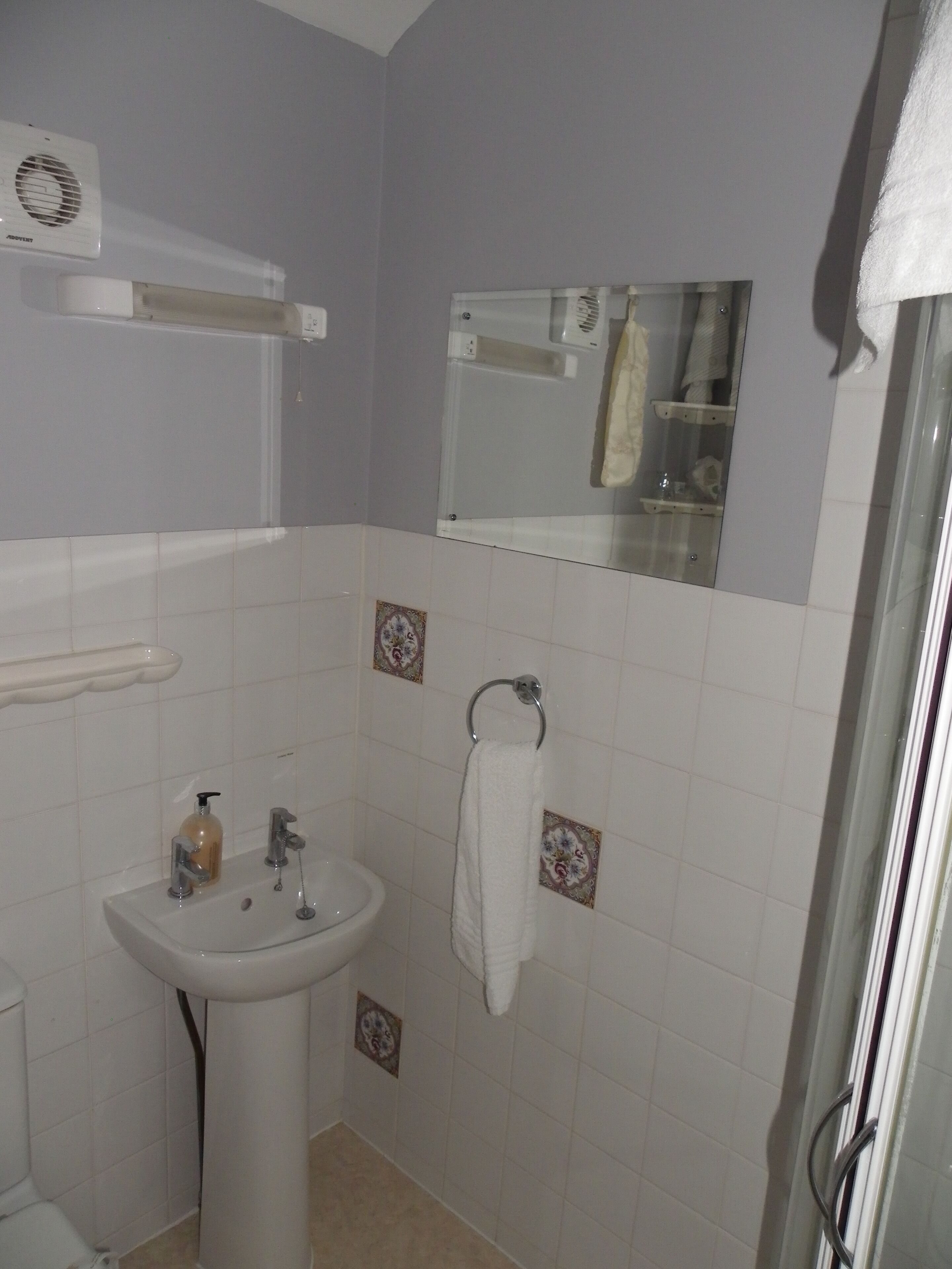 A bathroom with a sink, a mirror, and a shower.