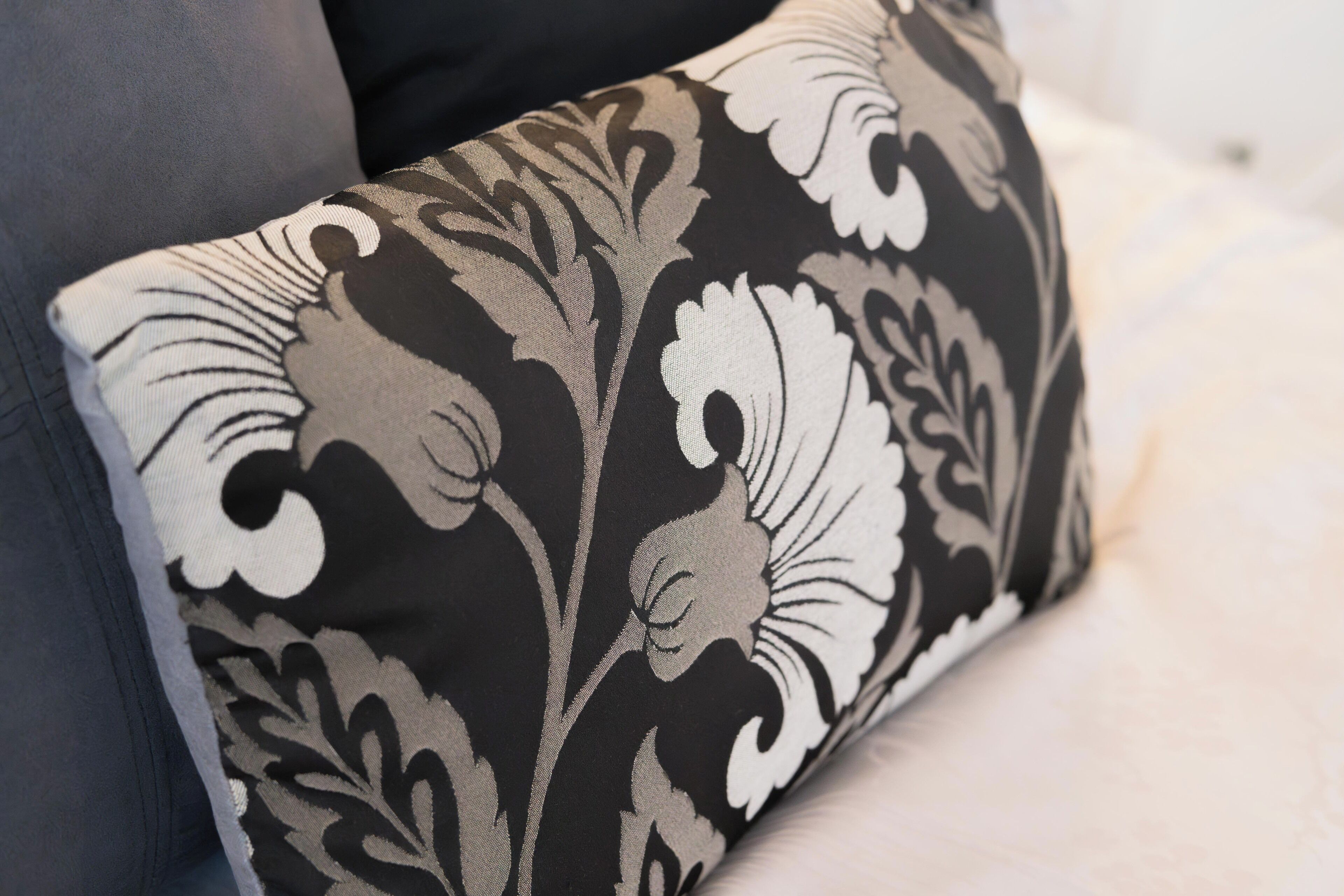A close-up of a black and white patterned pillow on a couch.