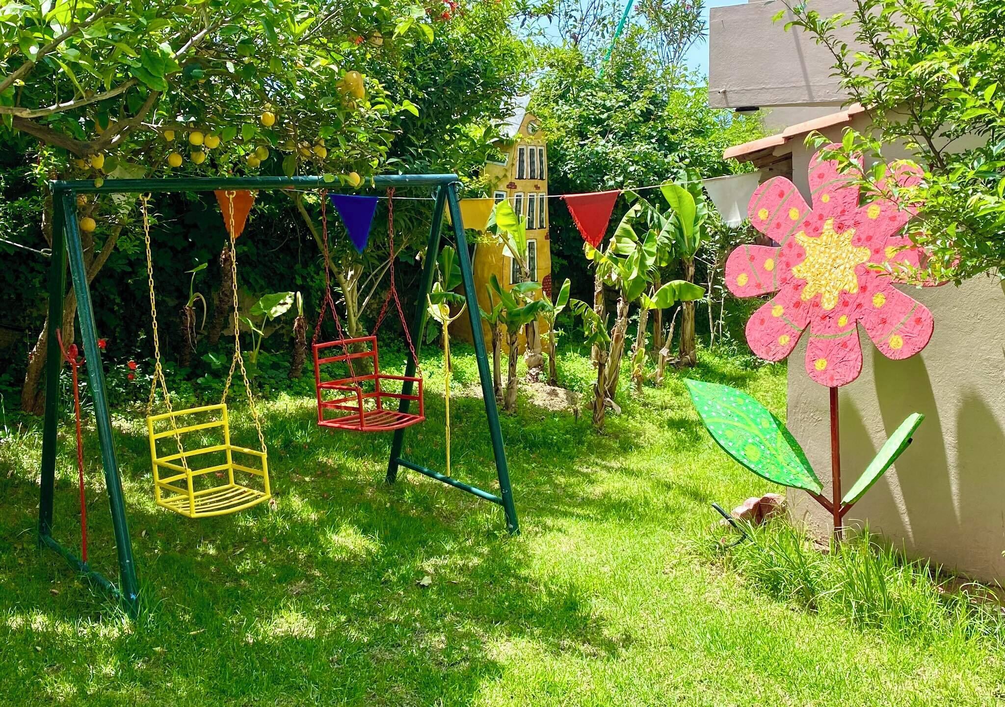 Ein Garten mit Schaukel und einer großen Blumenverzierung, im Hintergrund ein Haus.