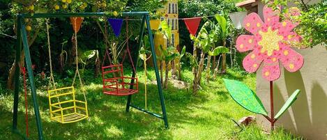 Ein Garten mit Schaukel und einer großen Blumenverzierung, im Hintergrund ein Haus.