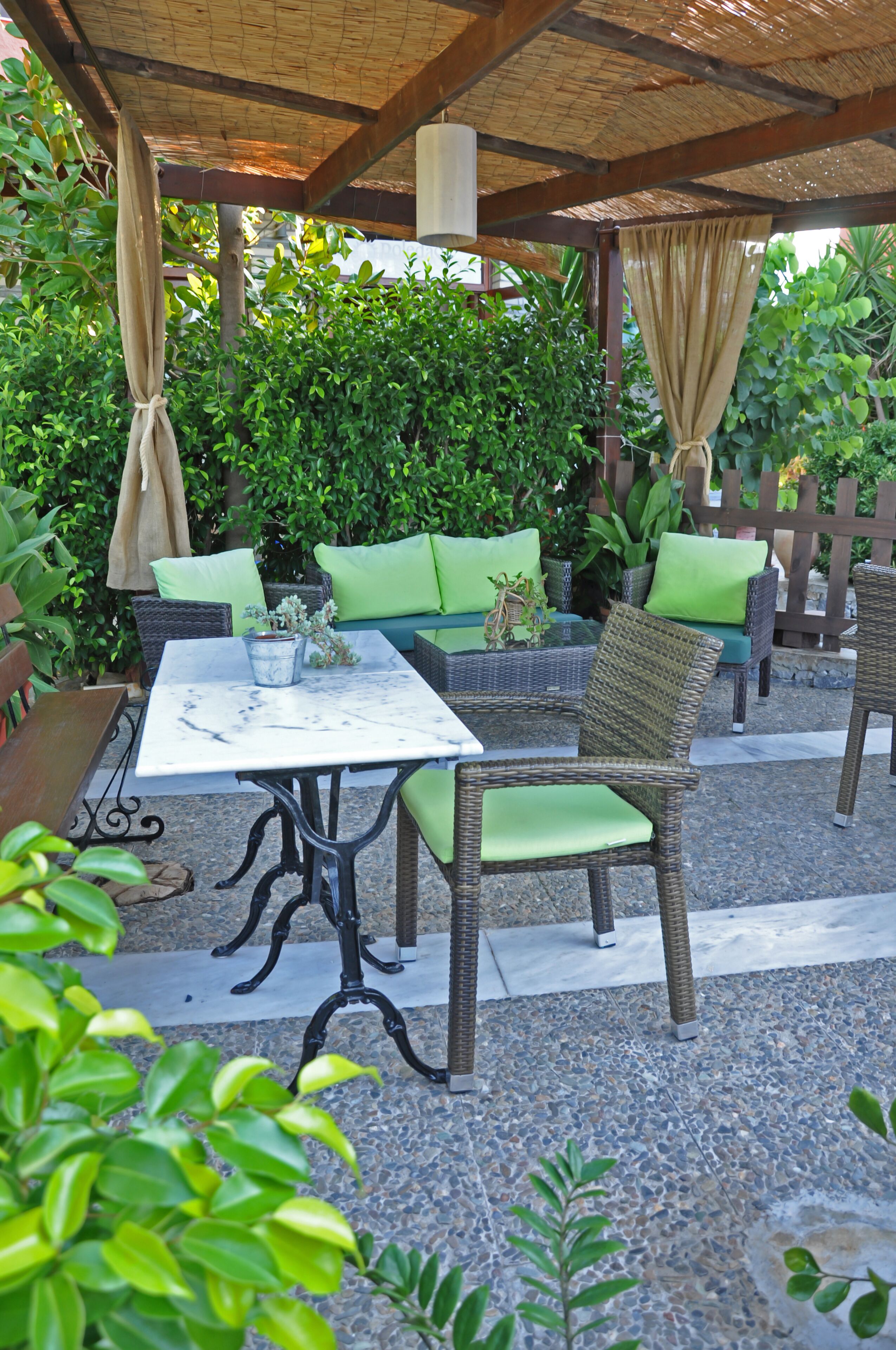 Un patio al aire libre con muebles de mimbre, una mesa y un sofá acolchado.