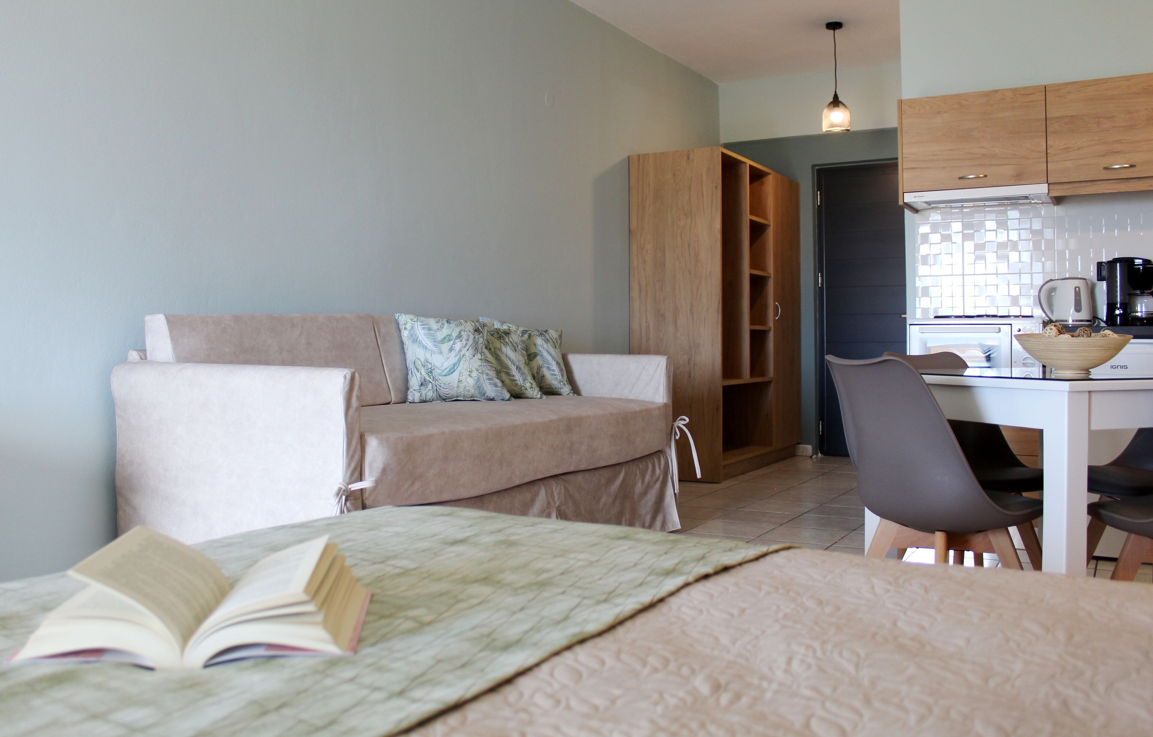 A cozy living area with a sofa, a dining table with chairs, and a kitchen area with cabinets and appliances.