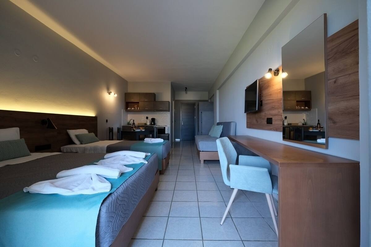 A modern hotel room with two beds, a desk, a chair, a TV, and a large mirror.