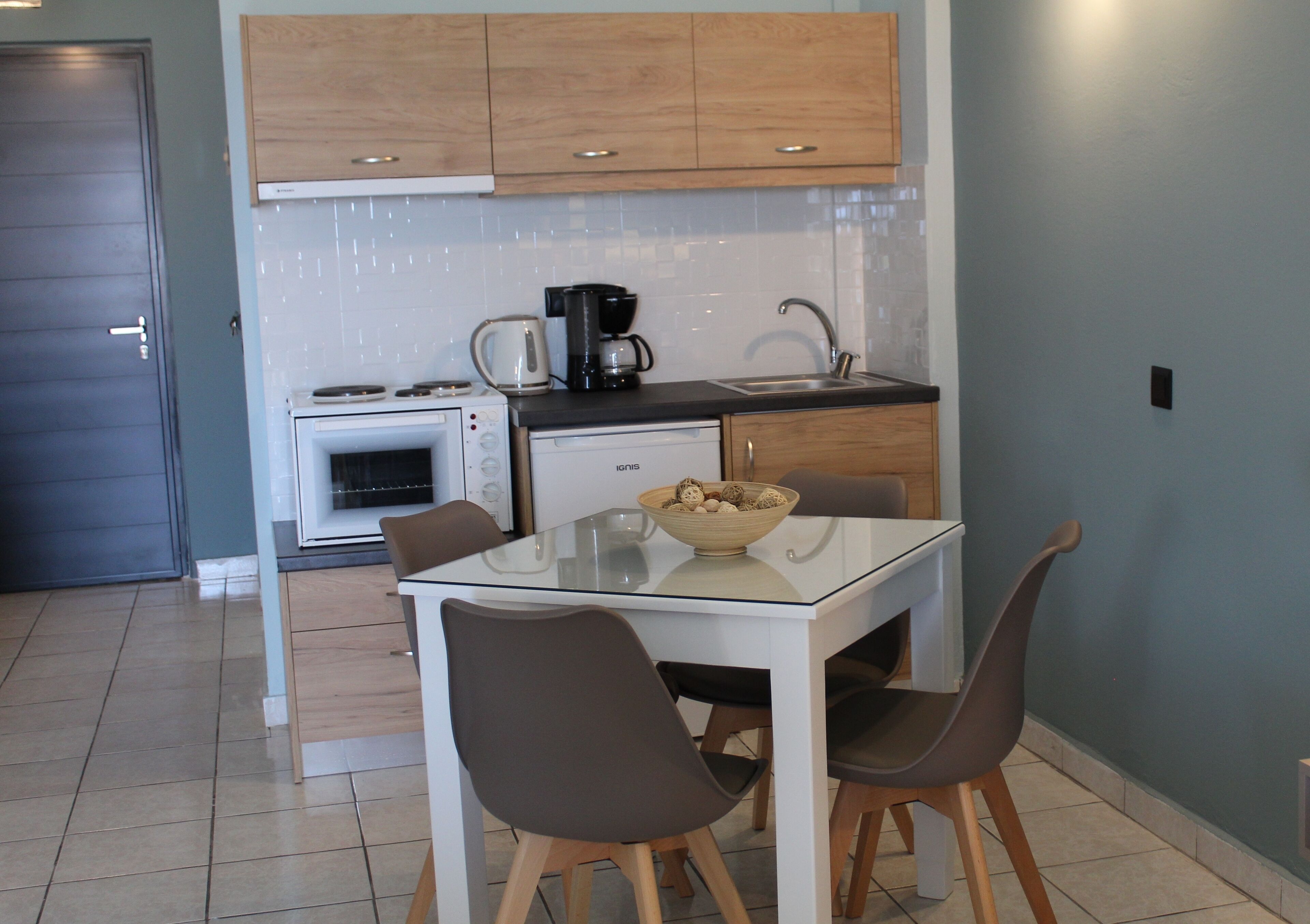 Una cocina moderna con una mesa de comedor, sillas, una cafetera y un tazón de bocadillos.
