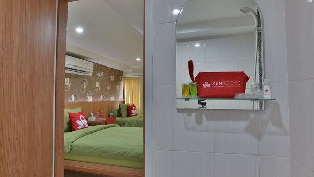 A hotel room with a bed, a mirror, and a shelf with toiletries. - ZEN Rooms Kampung Bali Tanah Abang (Jakarta)