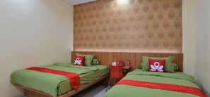 A hotel room with two beds, each with green bedding and red accents, a wooden headboard, and a patterned wallpaper. - ZEN Rooms Kampung Bali Tanah Abang (Jakarta)