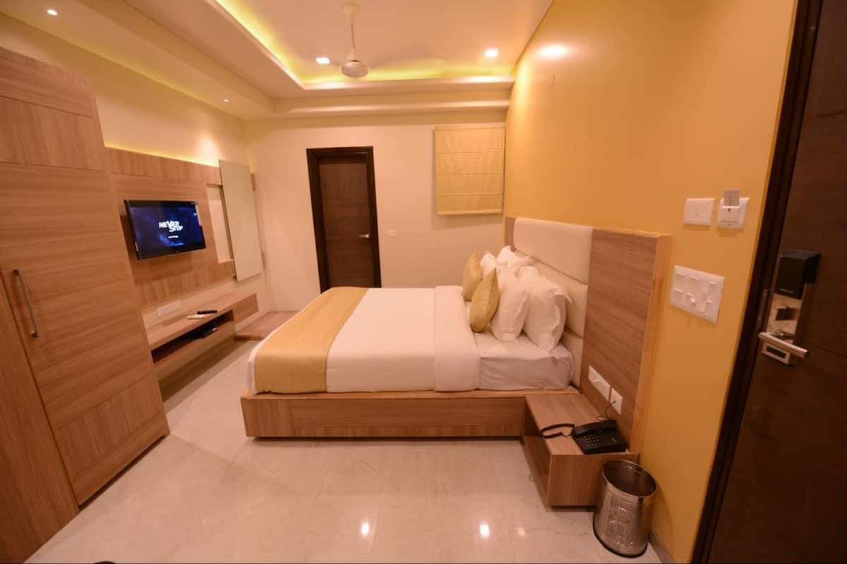 A modern bedroom with a bed, a television, and a wooden wardrobe.