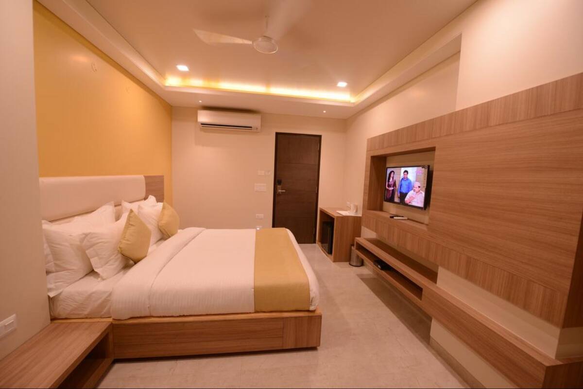 A modern hotel room with a bed, a TV, and a wooden accent wall.