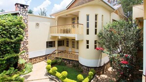 Une maison à deux étages avec une façade en pierre, un balcon et un jardin bien entretenu.