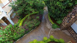 Une cour intérieure avec un mur en pierre, un sentier et diverses plantes.