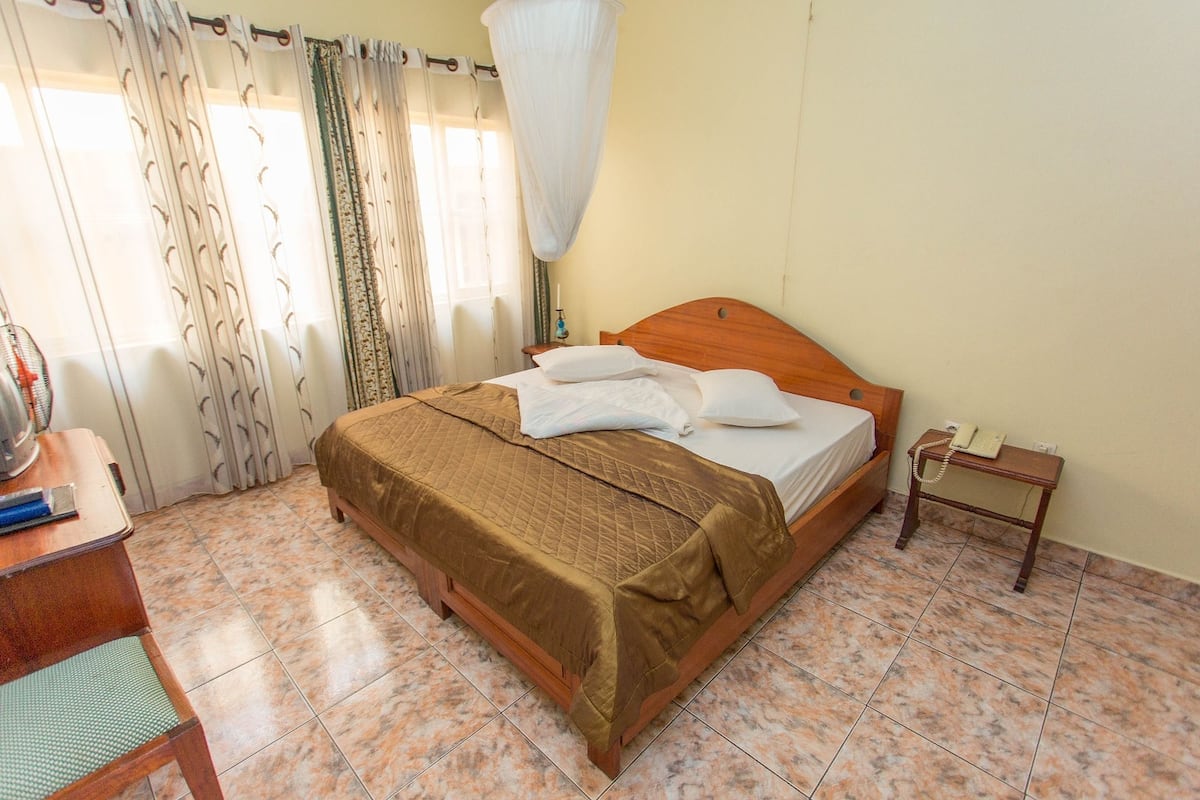 A bedroom with a bed, bedside table, and curtains.