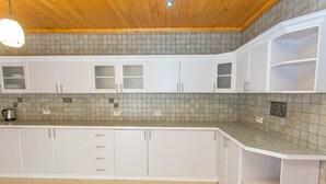Une cuisine avec des armoires blanches, un pare-feu en carrelage et un plafond en bois.