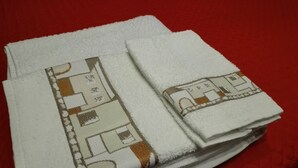 A stack of white towels with a brown and beige pattern, placed on a red textured surface. - Anita's House in the Heart of Segesta CIN IT081003C2BTVOXQJS  (Calatafimi)