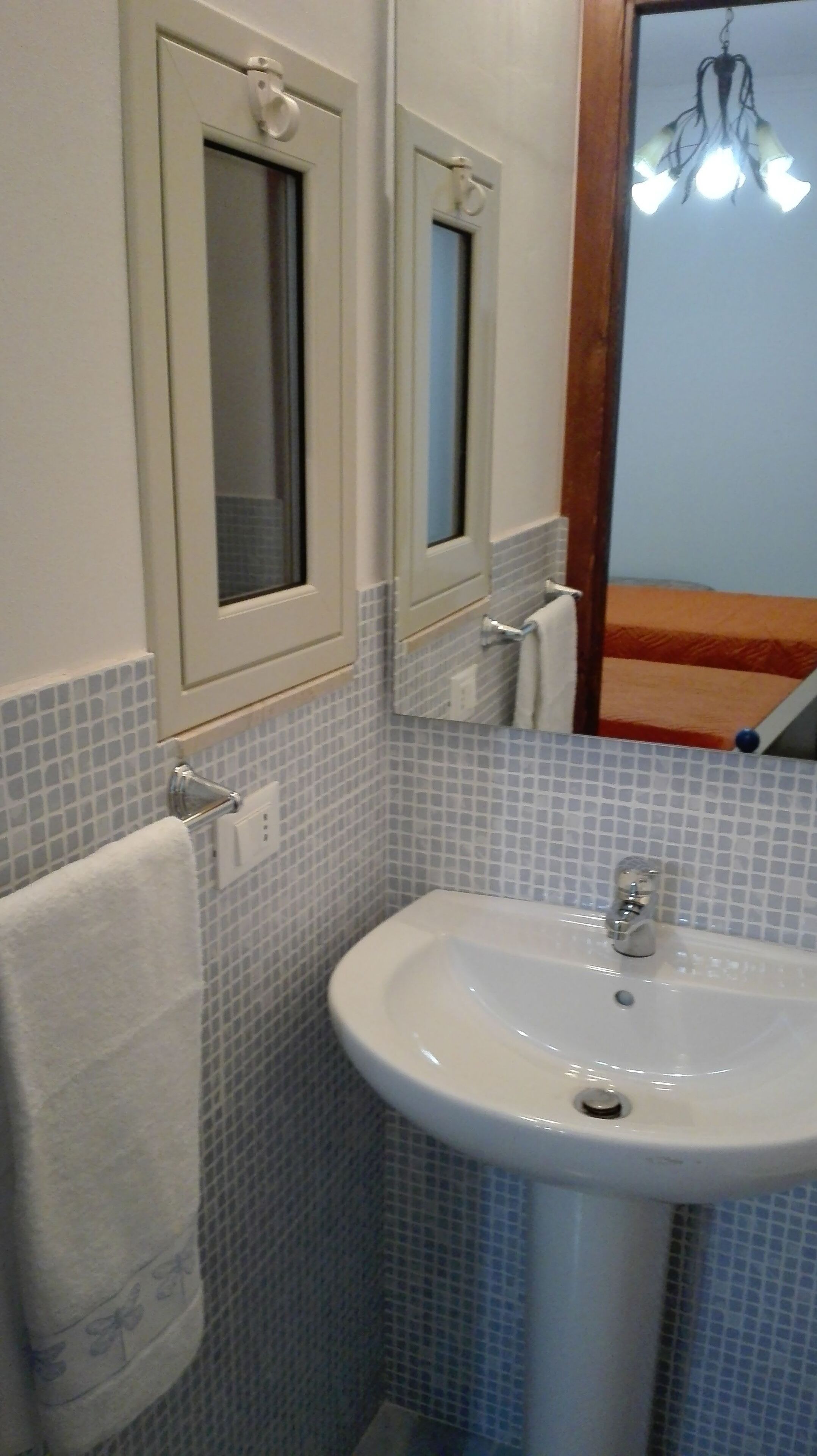 A bathroom with a white sink, a mirror, and a towel hanging on a rack.