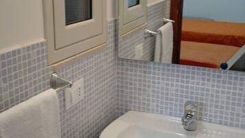 A bathroom with a white sink, a mirror, and a towel hanging on a rack.