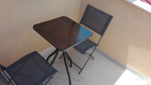 A small, dark-colored table with a single chair. The chair has a blue seat and backrest. - Anita's House in the Heart of Segesta CIN IT081003C2BTVOXQJS  (Calatafimi)