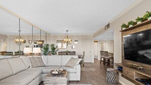 Een moderne woonkamer met een modulaire bank, een salontafel en een aan de muur bevestigde televisie.