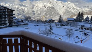 A snow-covered mountain village with traditional wooden buildings and a clear view of the mountains.