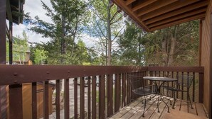 A wooden deck with a table and chairs, overlooking a driveway and trees. - JHRL - Sleeping Indian West #10 (Teton Village)