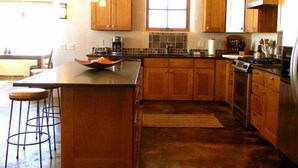 A kitchen with wooden cabinets, a central island, bar stools, and a stainless steel refrigerator.