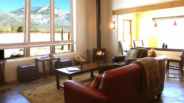 A cozy living room with a fireplace, large windows, and a view of mountains.