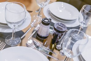 Une table dressée avec de l’argenterie, des assiettes blanches et des verres transparents.