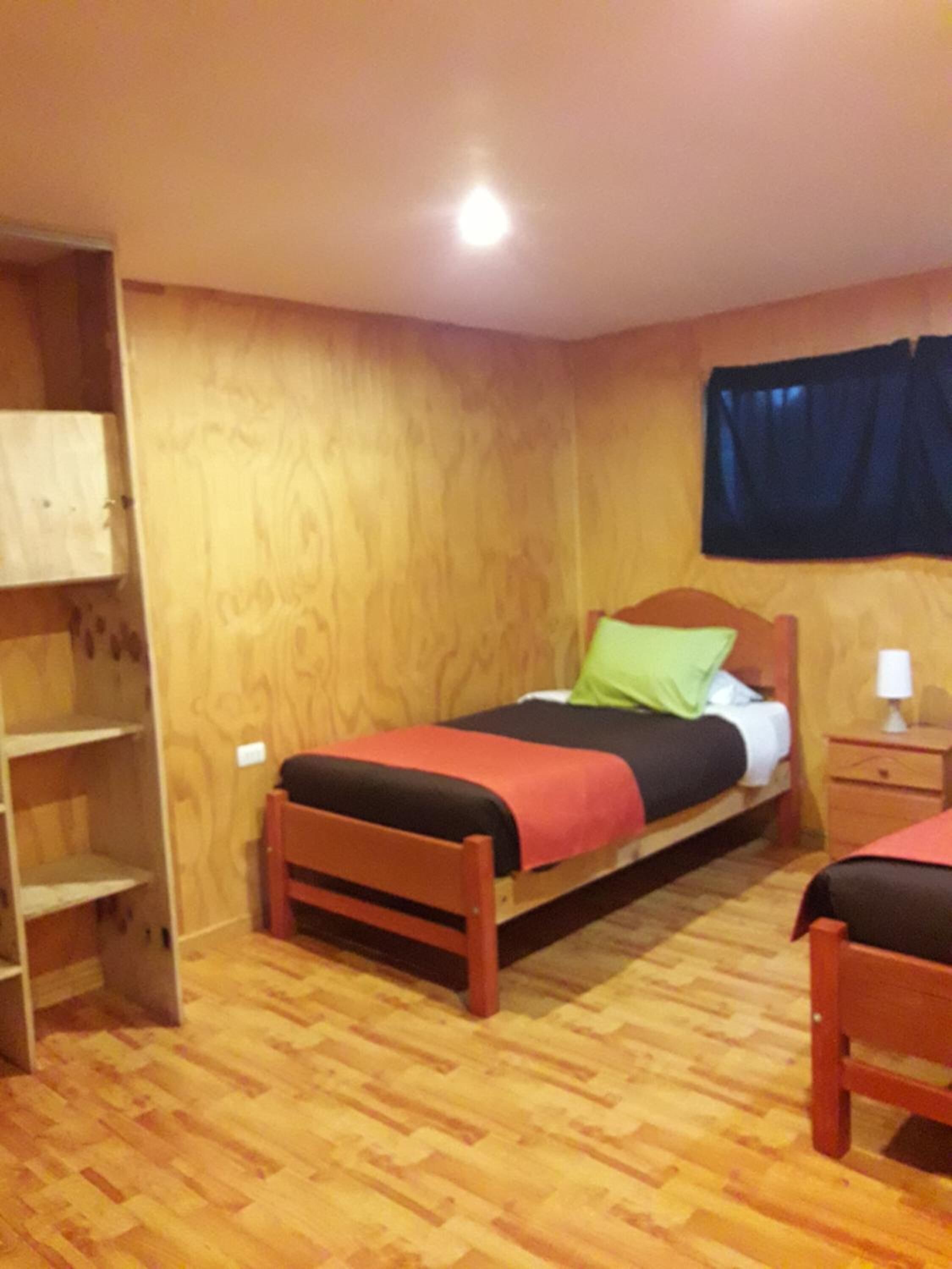 Una habitación con dos camas de madera, un armario de madera y piso de madera.