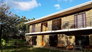 A two-story house with a stone facade, large windows, and a balcony. - La Casa del Kori - Hostal - Hostel (Hanga Roa)