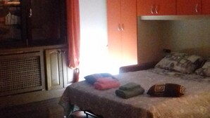 A bedroom with a bed, a wardrobe, and a chair. - Ghirla lake. Studio flat (Ghirla)